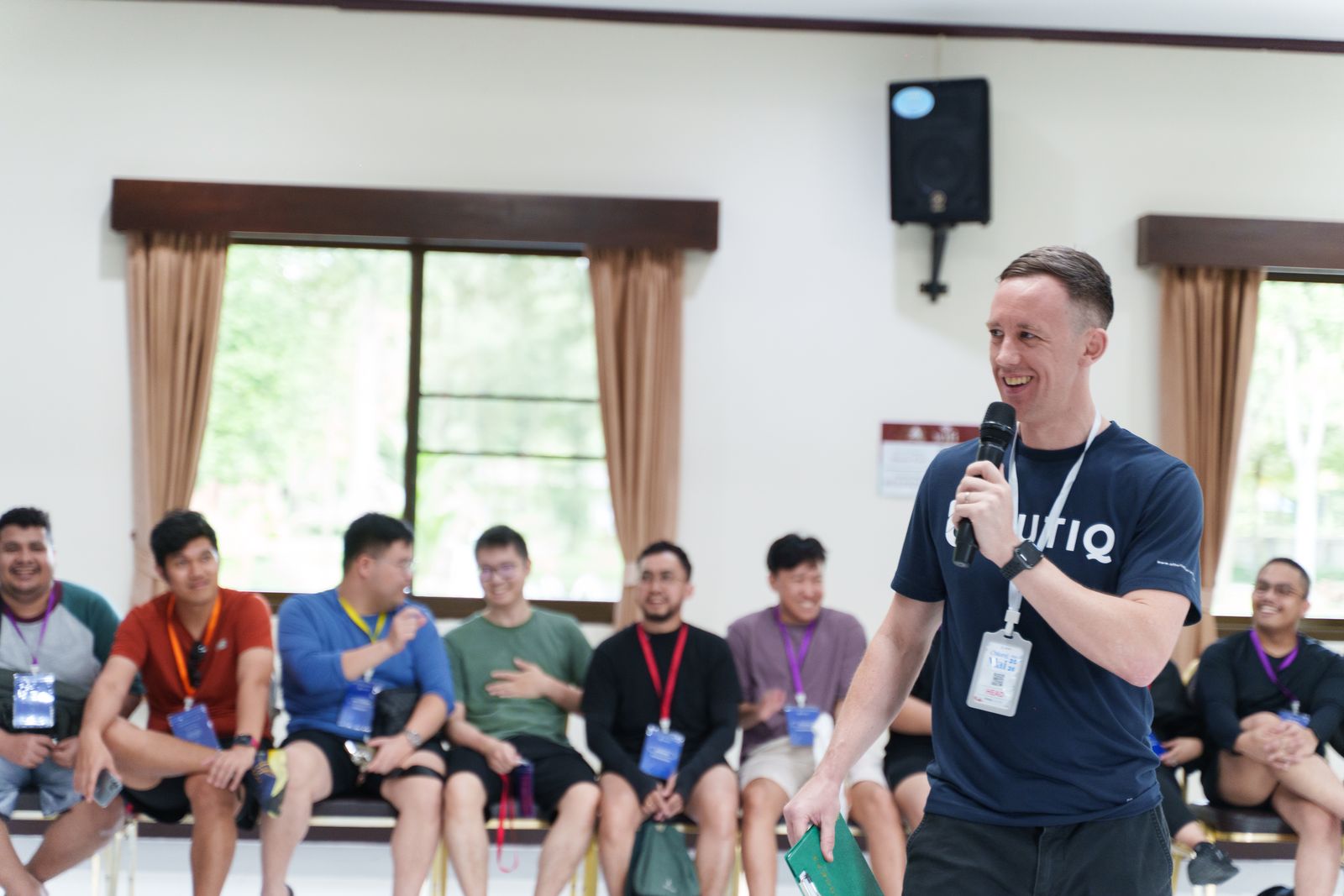 Phill Savage, founder of Unboring Teams, laughing with a microphone while facilitating an interactive team workshop in Chiang Mai, Thailand